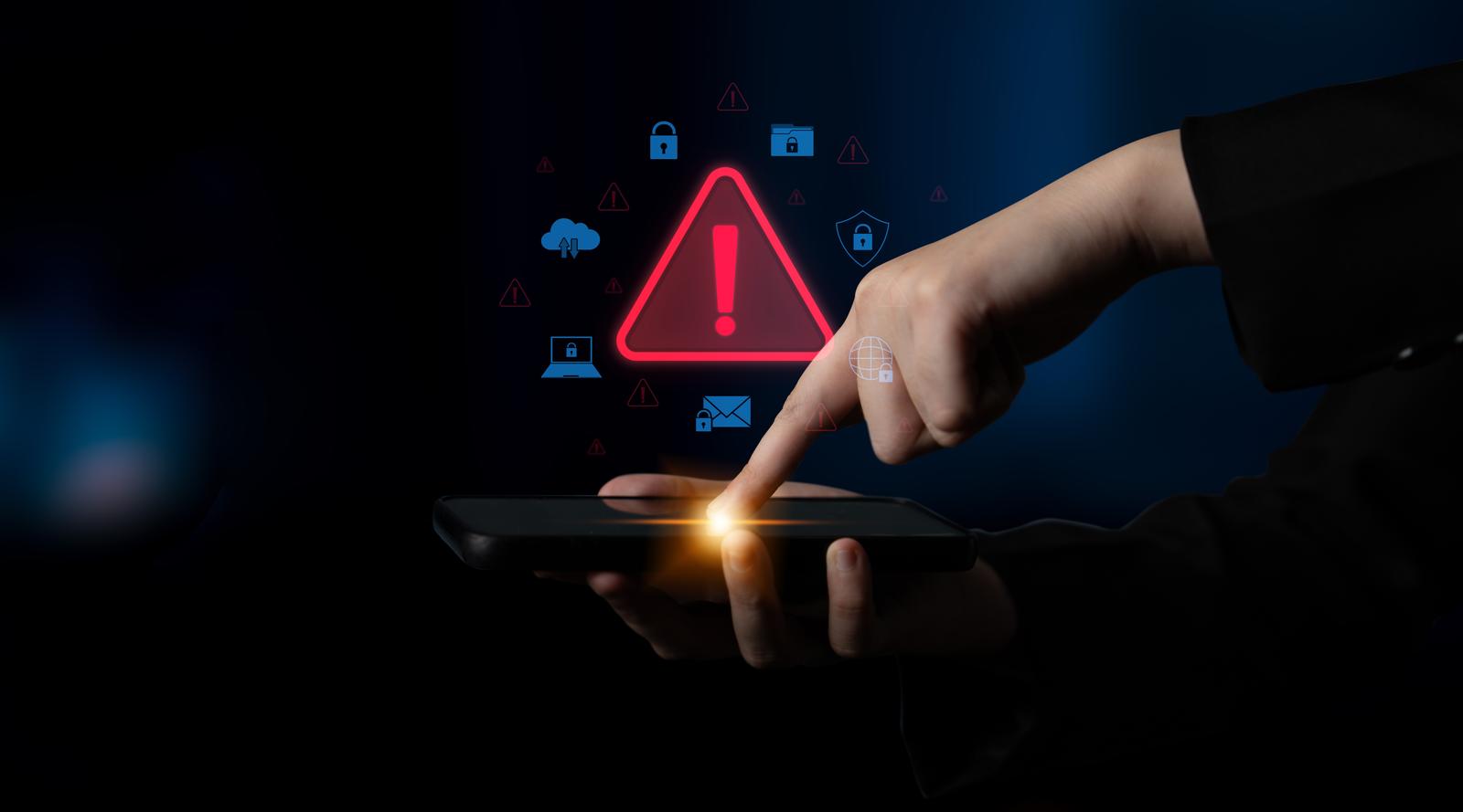 A hand tapping a smartphone with glowing warning icons, symbolizing cybersecurity threats and digital protection.