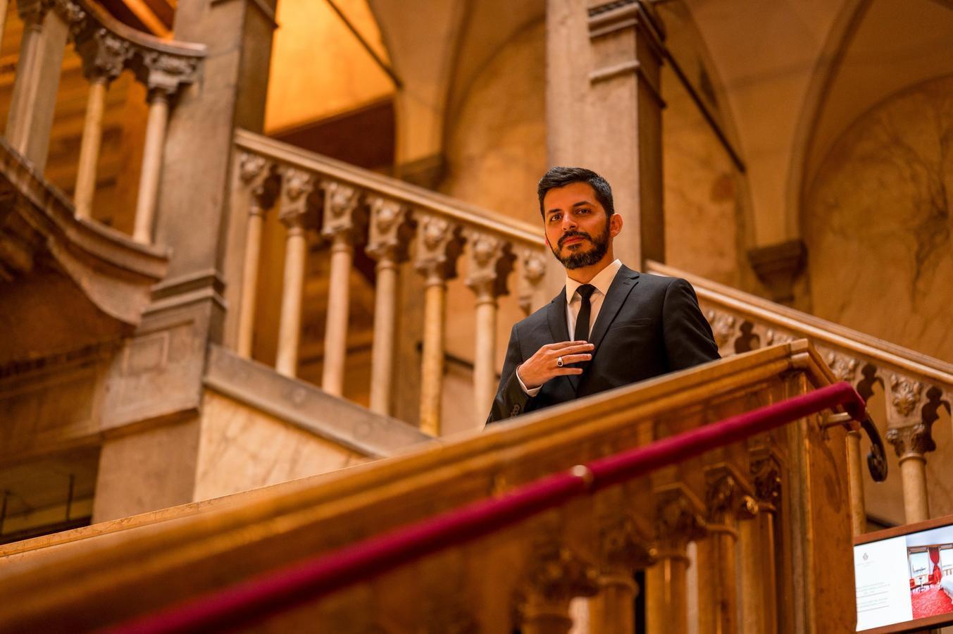 Saudi actor Aziz Gharbawi, dressed in a black suit, standing on a grand staircase in a historic building—part of a new generation of performers shaping Saudi Arabia’s emerging film industry.
