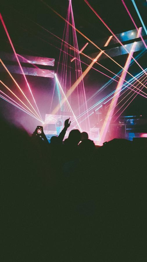 DJ performing under colorful laser lights in front of a cheering crowd, representing the growing legitimacy of creative careers once considered unconventional.