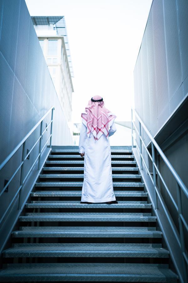 With 67% of its population under 30, a young man stands on stairs symbolizing Saudi Arabia's youth as a driving force for economic diversification and modernization.