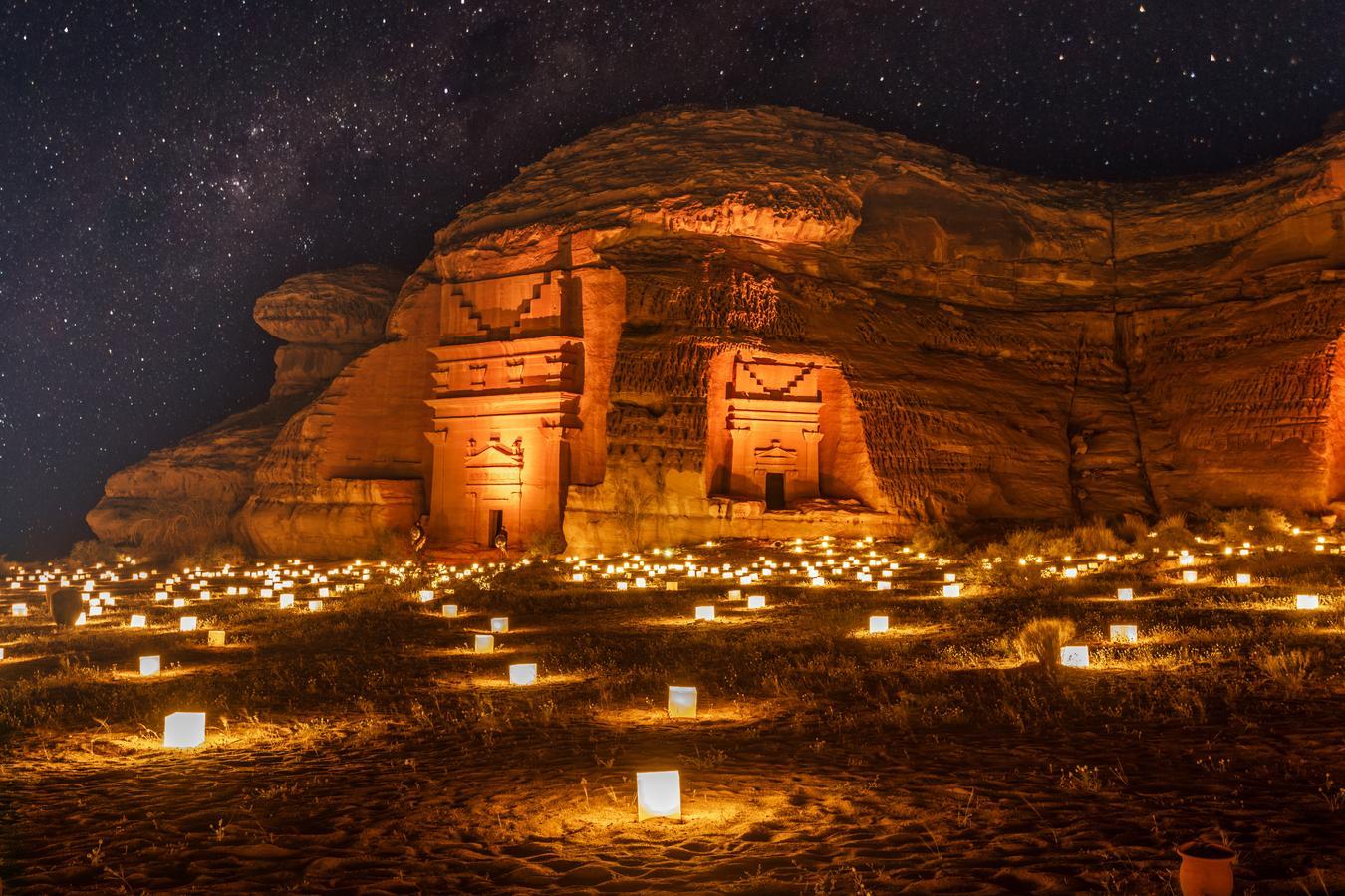 The illuminated Nabataean tombs of AlUla, Saudi Arabia, framed by lanterns and a starry sky, showcase the intersection of ancient heritage and modern cultural revival.
