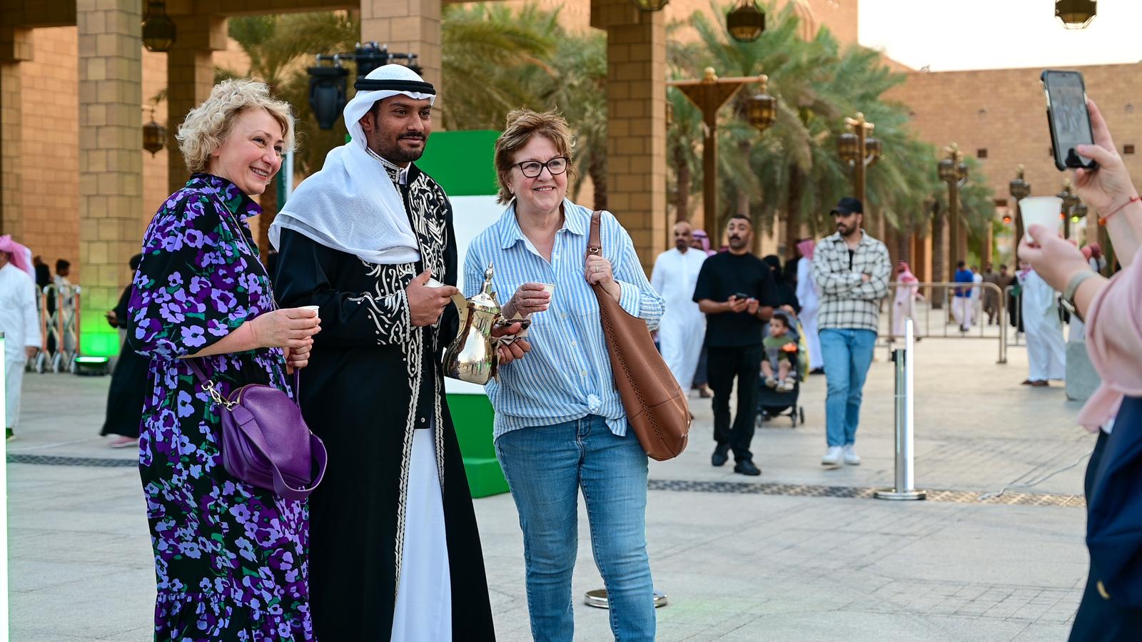 Visitors in Riyadh’s historic Justice Palace district wearing modest clothing while receiving traditional Saudi coffee, illustrating the balance between changing dress norms and enduring customs.