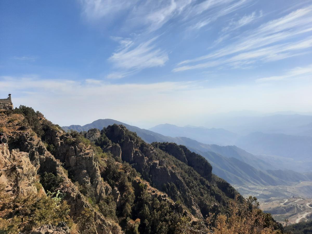 A high-altitude mountain landscape in Al Soudah, Abha, featuring lush green hills covered in rolling fog.